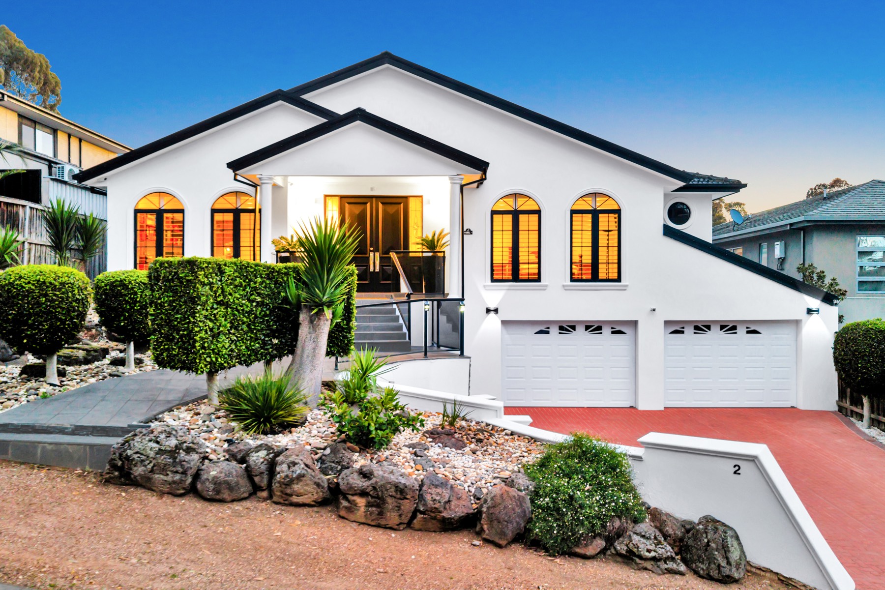 Drone photograph of a white two-storey home lit up at dusk