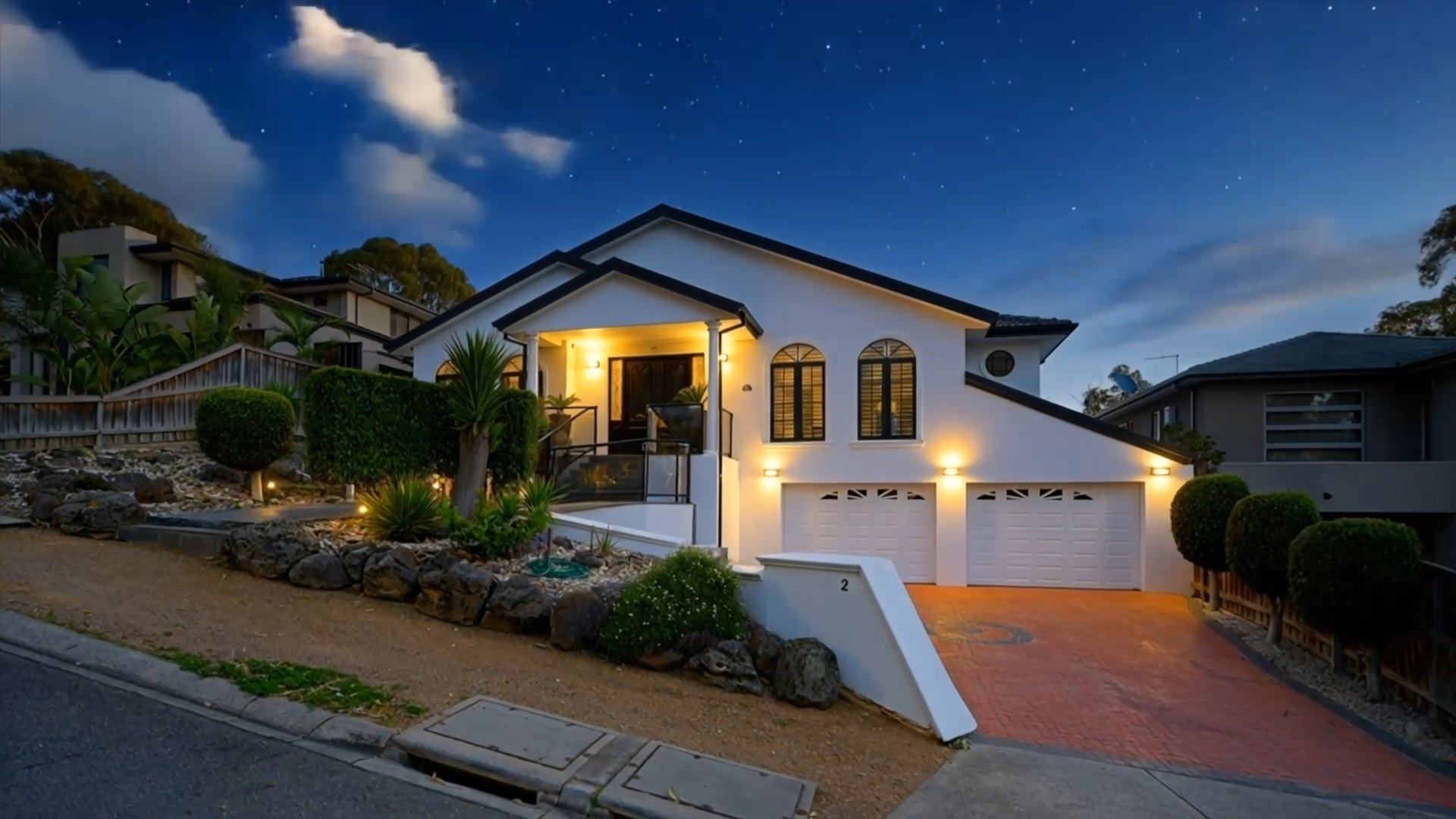 White home lit up at twilight under a starry sky